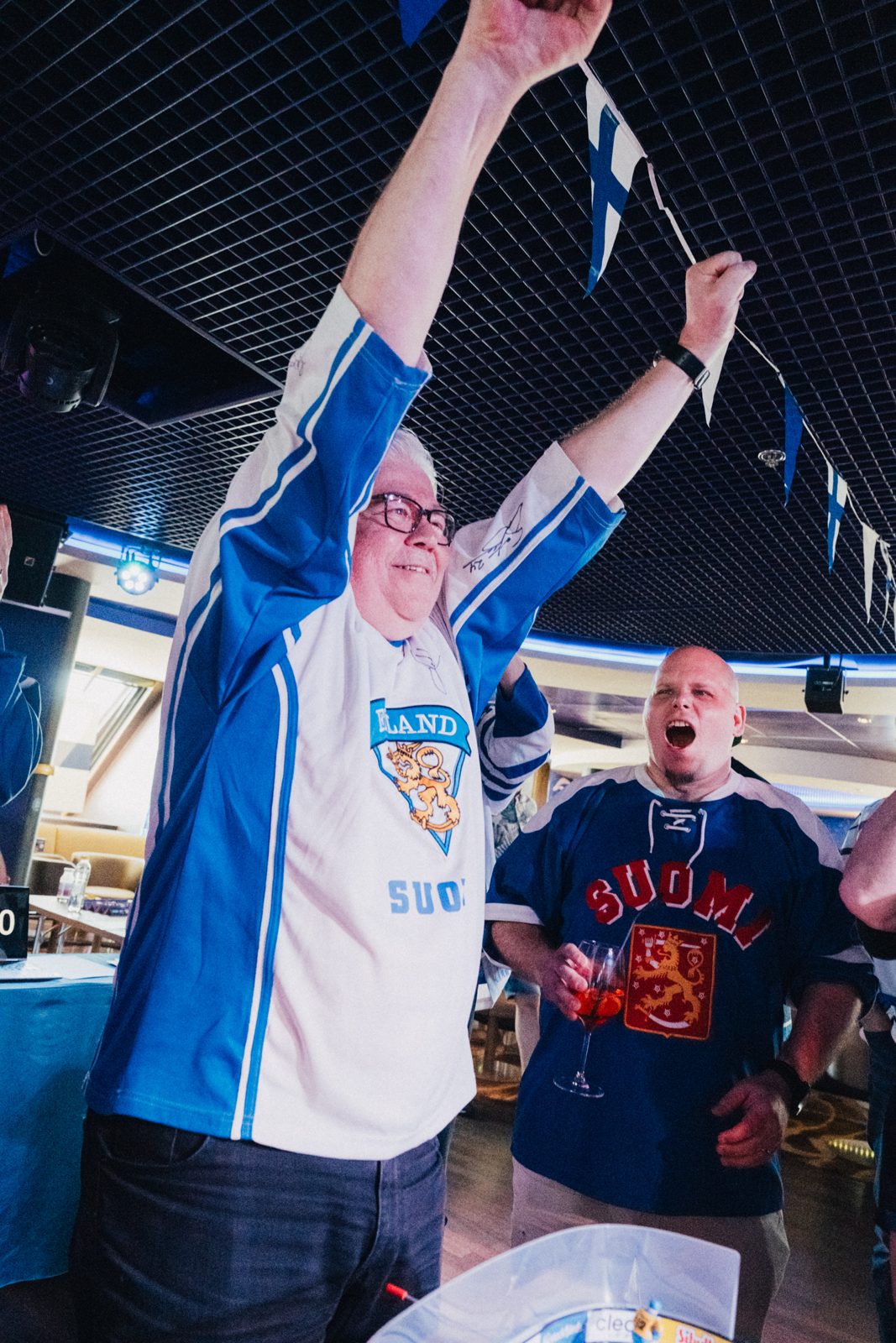 Fanit hurraavat Suomen lippuja heiluttaen kisatunnelmissa